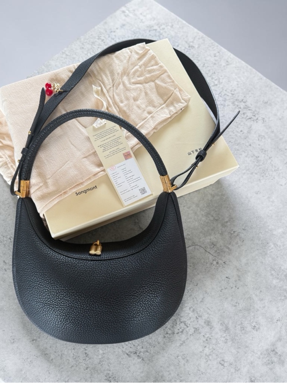 Songmont Black Pebbled Leather Crescent Shoulder Bag with Gold Accents